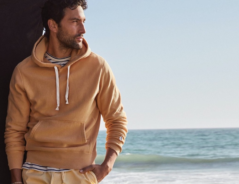 Going casual, Noah Mills wears a Todd Snyder + Champion sun-faded midweight popover hoodie with a Todd Snyder basic stripe tee.