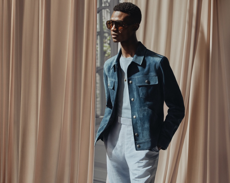 Model Jason Harderwijk dons a Tom Ford t-shirt with a blue suede trucker jacket, brown aviator-style tortoiseshell acetate sunglasses, and silk and linen-blend suit trousers