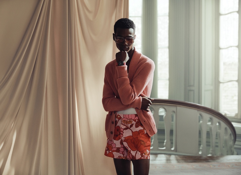 Front and center, Jason Harderwijk wears Tom Ford's pink ribbed cashmere cardigan, gray round-frame acetate sunglasses, and slim-fit floral print swim shorts.