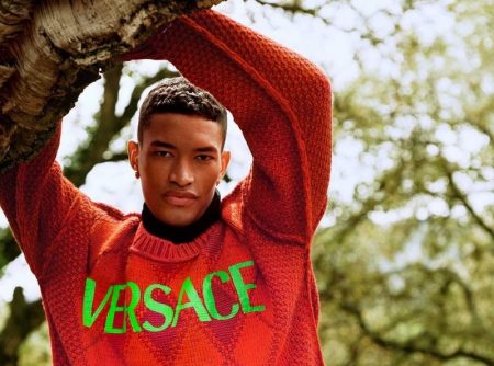 Raphael Balzer dons a logo-adorned argyle sweater for Versace's pre-fall 2021 men's campaign.