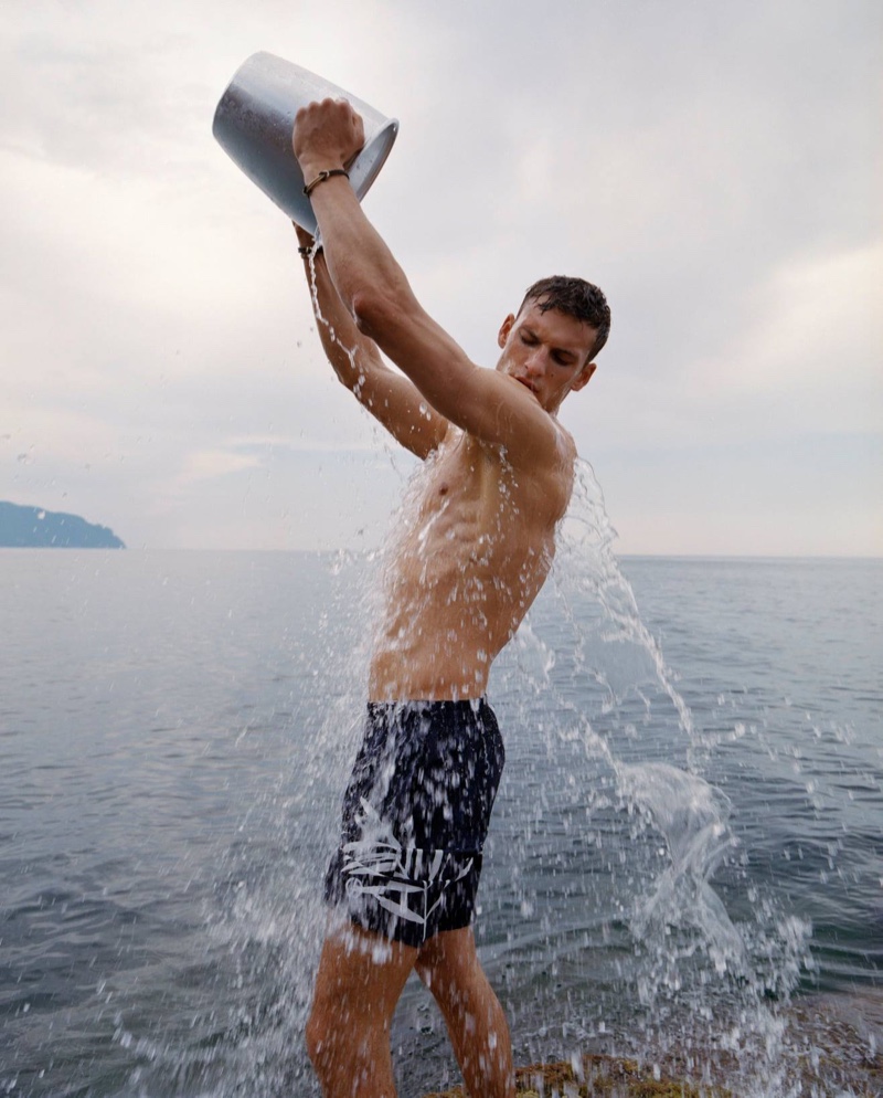 Staying cool, David Trulik wears swim shorts from Giorgio Armani for the brand's summer 2021 men's campaign.