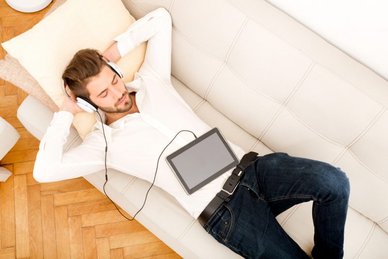 Man Laying Down on Couch Listening to Music with Headphones