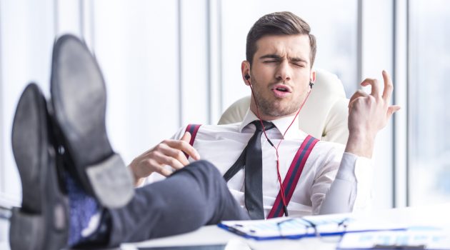 How Listening to Music Can Make You More Productive Man at Desk in Office Listening to Music