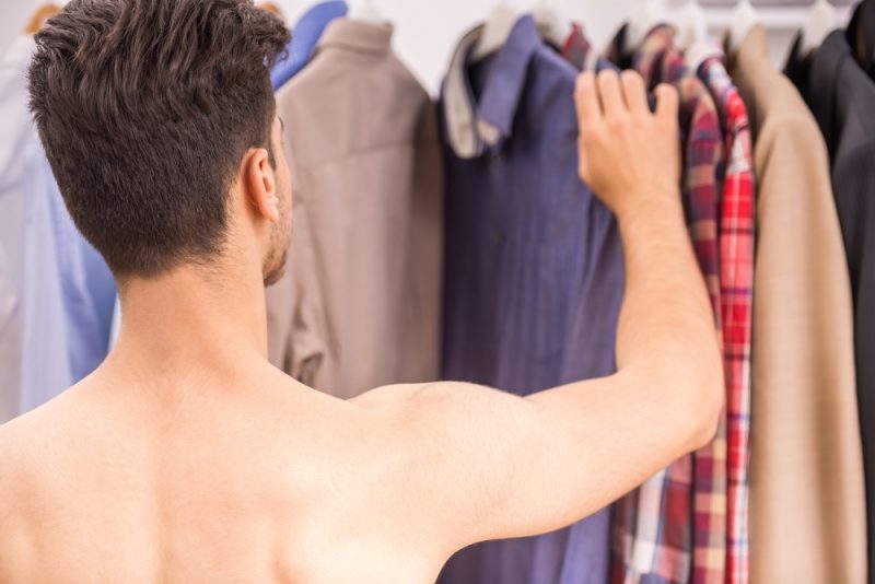 Young Man Looking Through Clothes Shirtless