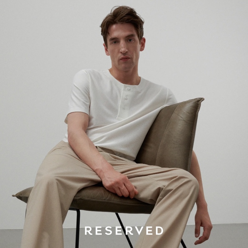 Front and center, Anatol Modzelewski wears a short-sleeve henley top with khaki pants by Reserved.