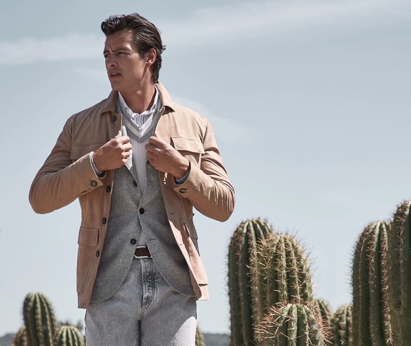 Mixing neutrals, Harry Gozzett dons a four pocket jacket over a blazer, v-neck sweater, and striped shirt with denim jeans by Brunello Cucinelli.