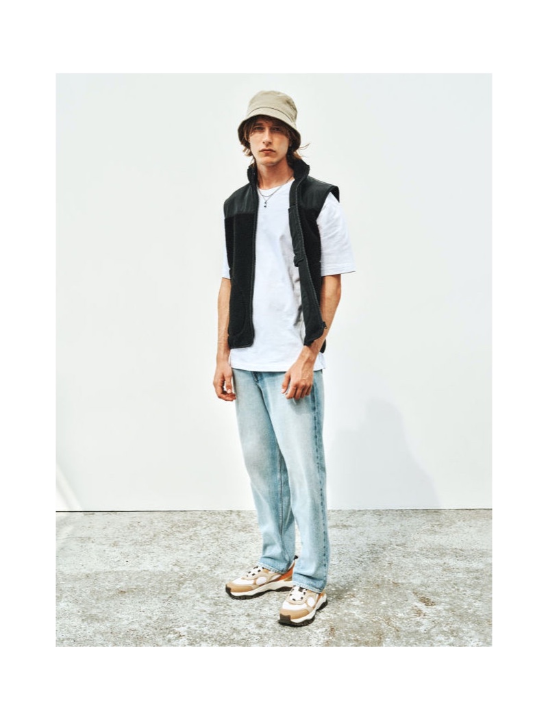 Front and center, Oscar Asberg models H&M's relaxed-fit denim jeans with a t-shirt and vest.