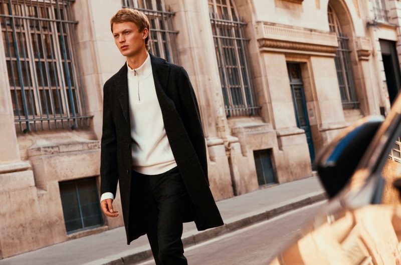 Model Jonas Glöer sports a Massimo Dutti coat with a half-zip pullover and pants.