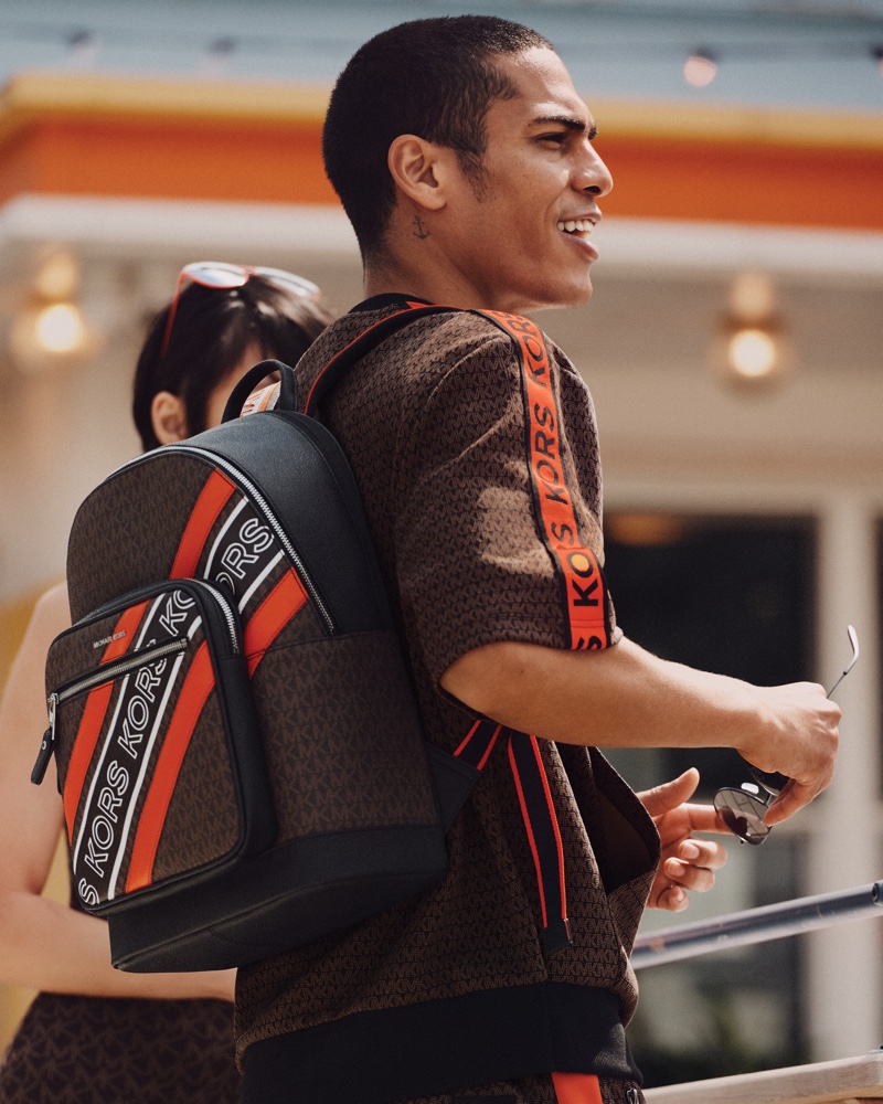 Taking hold of a MK monogram print backpack, Geron McKinley fronts MICHAEL Michael Kors' #MKGO fall-winter 2021 campaign.