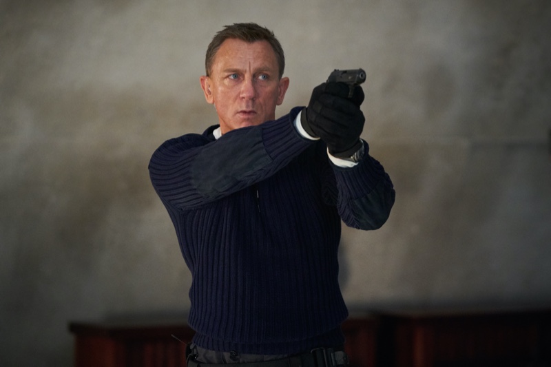 Sporting a cable-knit sweater with elbow patches, Daniel Craig reprises his role as James Bond in a still from "No Time to Die."