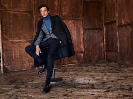 Donning a coat draped over his shoulders, Alexis Maçon-Dauxerre also models a check suit jacket and turtleneck from Luigi Bianchi Mantova.