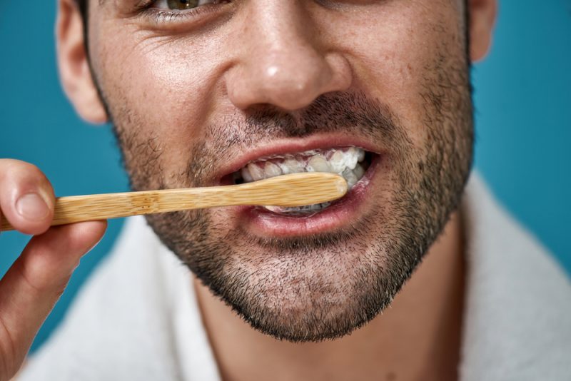 Man Brushing Teeth with Wooden Toothbrush Closeup