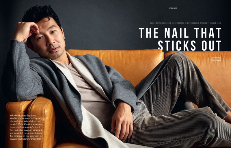 Lounging on a couch, Simu Liu wears an Armani coat and corduroy trousers with a Brioni sweater for Esquire Singapore.