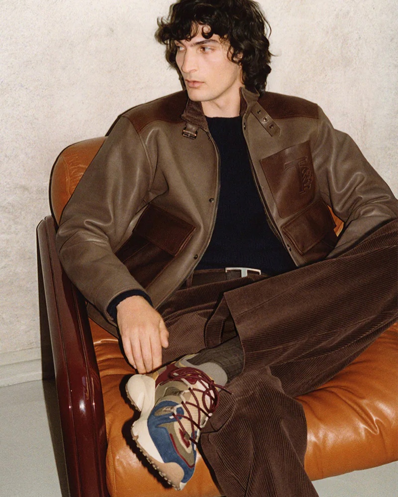 Donning a brown leather jacket with corduroy pants, Luca Lemaire showcases a new pair of sneakers for Tod's fall-winter 2021 men's campaign.