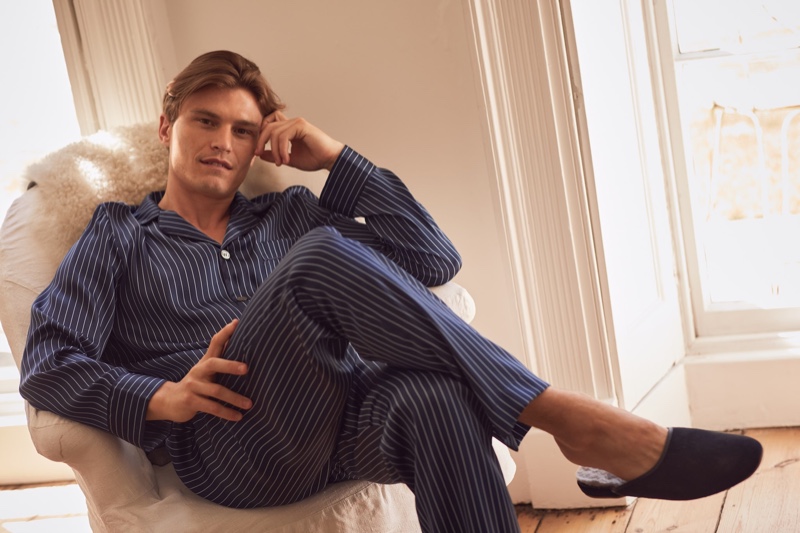 Lounging, Oliver Cheshire wears a pair of Derek Rose's silk pajamas.