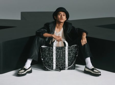 Posing with an oversized bag, Yudai Tateishi wears printed black and white loafers from the Jimmy Choo x Eric Haze collection.