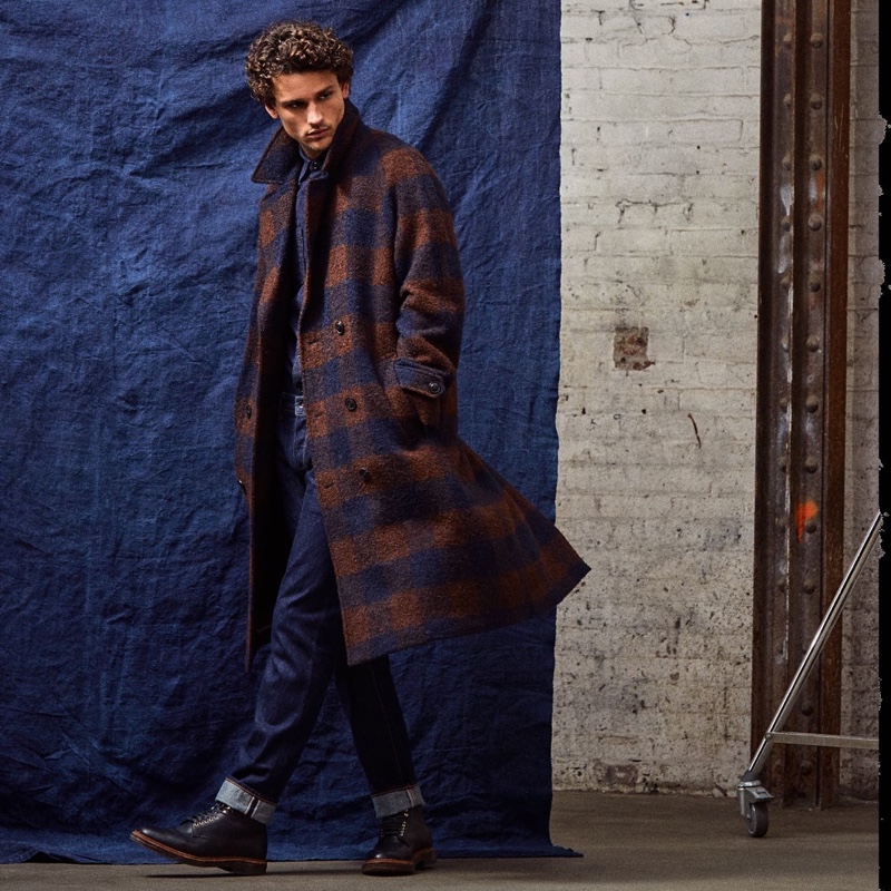 Simon Nessman wears an Italian double-breasted topcoat in brown navy check slim-fit stretch jeans by Todd Snyder.