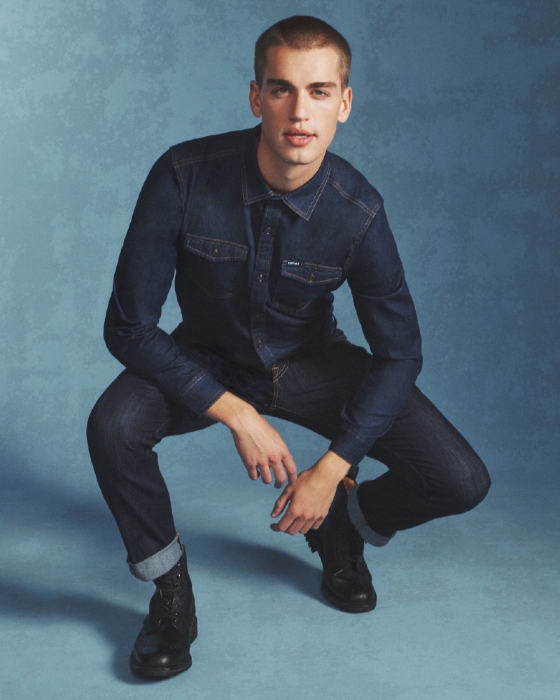 Model Jake Hart doubles down on denim, wearing a indigo blue denim shirt with matching cuffed jeans from Buffalo David Bitton.