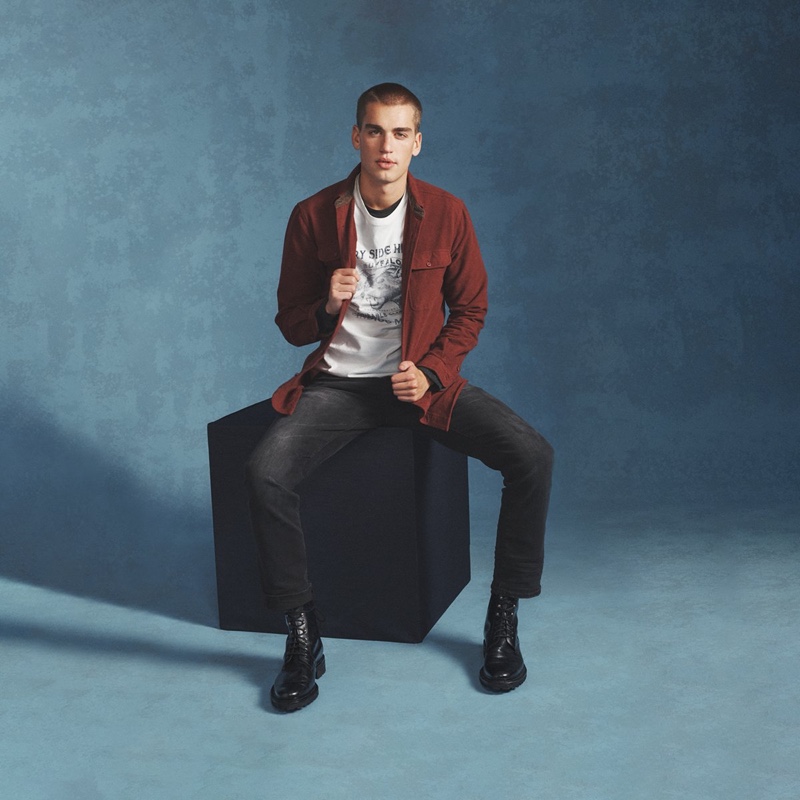Taking to the photo studio, Jake Hart rocks a long-sleeve shirt with a graphic tee and jeans from Buffalo David Bitton.