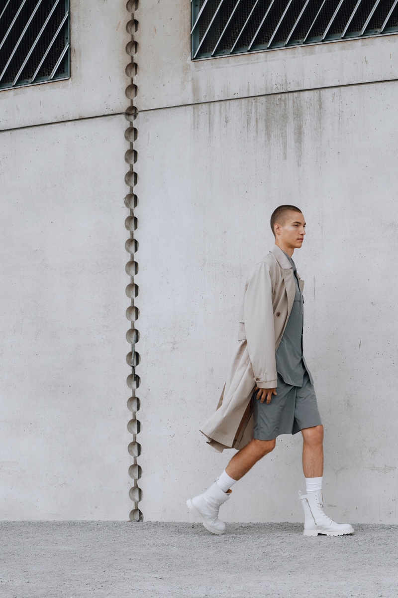 Embracing a monochromatic color scheme, David Shyn dons Filippa K's trench coat with a nylon overshirt, shorts, and lace-up boots.