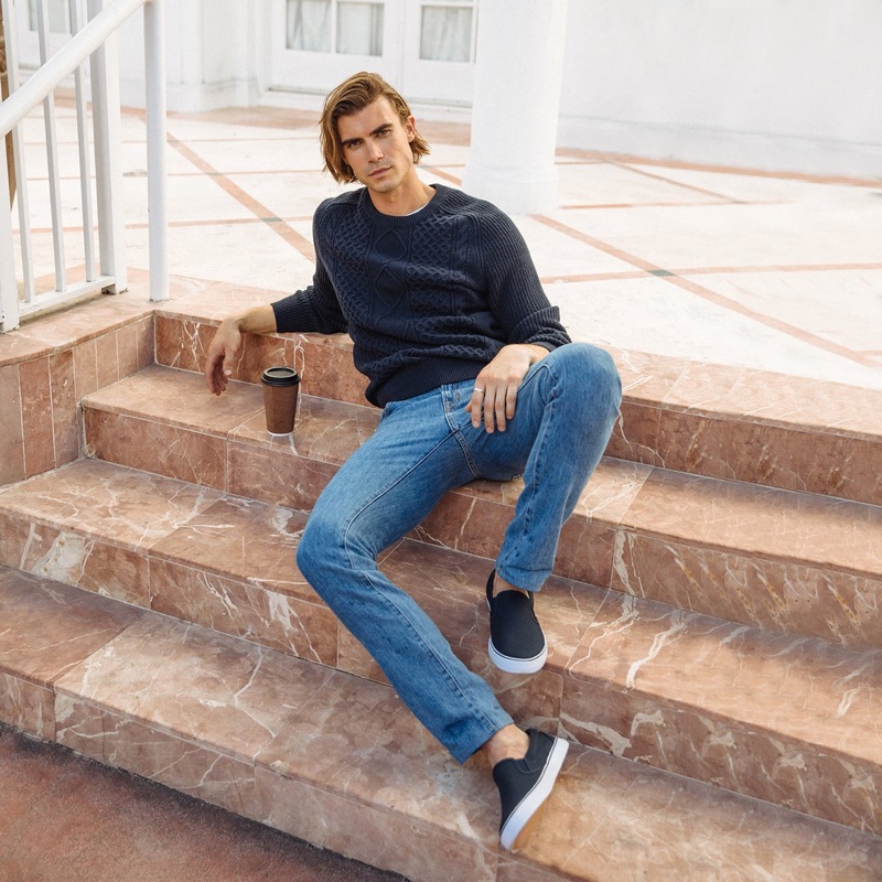 Alexander Command relaxes in a pair of Peluro's medium wash denim jeans.