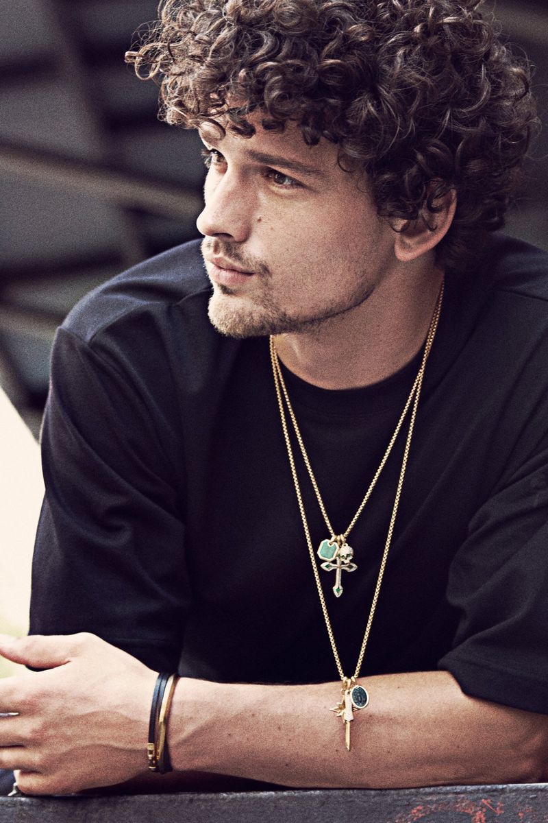 Layering David Yurman necklaces for the brand's fall-winter 2021 campaign, Simon Nessman dons a skull, gothic cross, dagger, Petrvs bee, and Roman amulets.