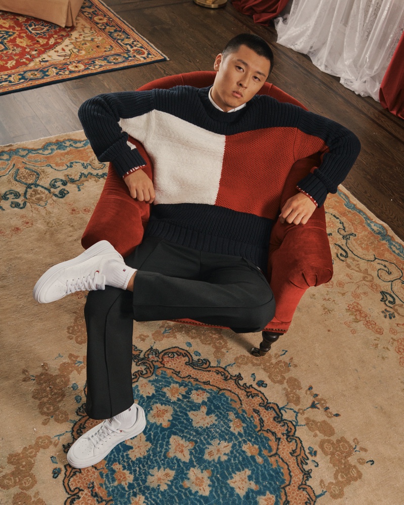Hanwei Guo wears Tommy Hilfiger's signature red, white, and blue flag sweater for the brand's holiday 2021 campaign.