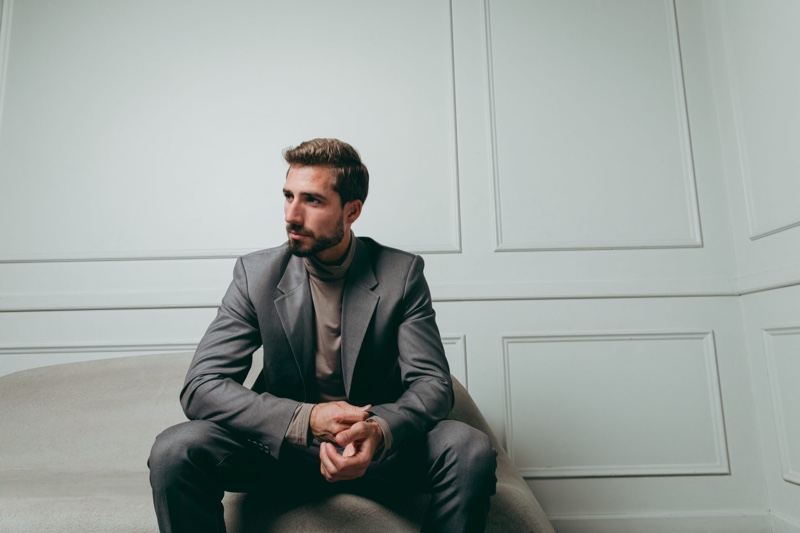 Kevin Trapp dons a charcoal-colored suit with a roll neck top from his ABOUT YOU capsule collection.