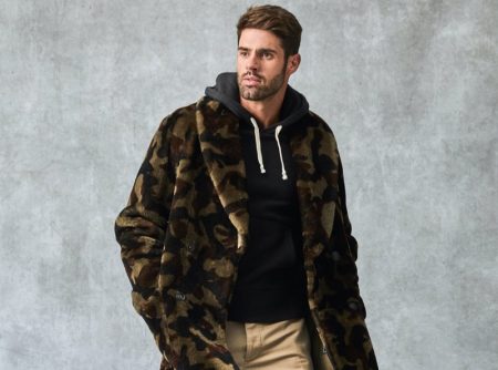 Making a graphic statement, Chad White models a Todd Snyder Italian shearling double-breasted shawl coat with a camouflage print. He also dons a Todd Snyder + Champion full-zip hoodie, Todd Snyder slim-fit tab front stretch chinos, and Tricker's + Todd Snyder stow boots.