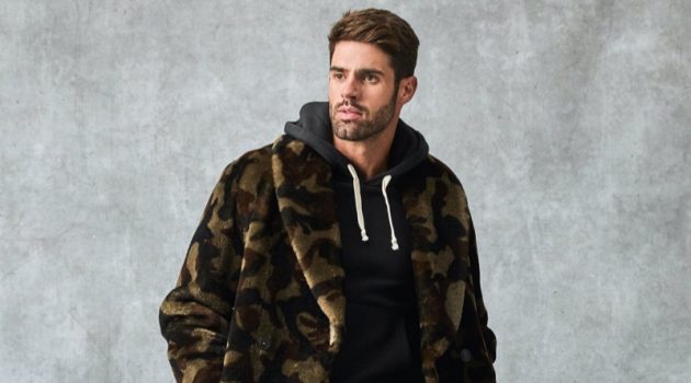 Making a graphic statement, Chad White models a Todd Snyder Italian shearling double-breasted shawl coat with a camouflage print. He also dons a Todd Snyder + Champion full-zip hoodie, Todd Snyder slim-fit tab front stretch chinos, and Tricker's + Todd Snyder stow boots.