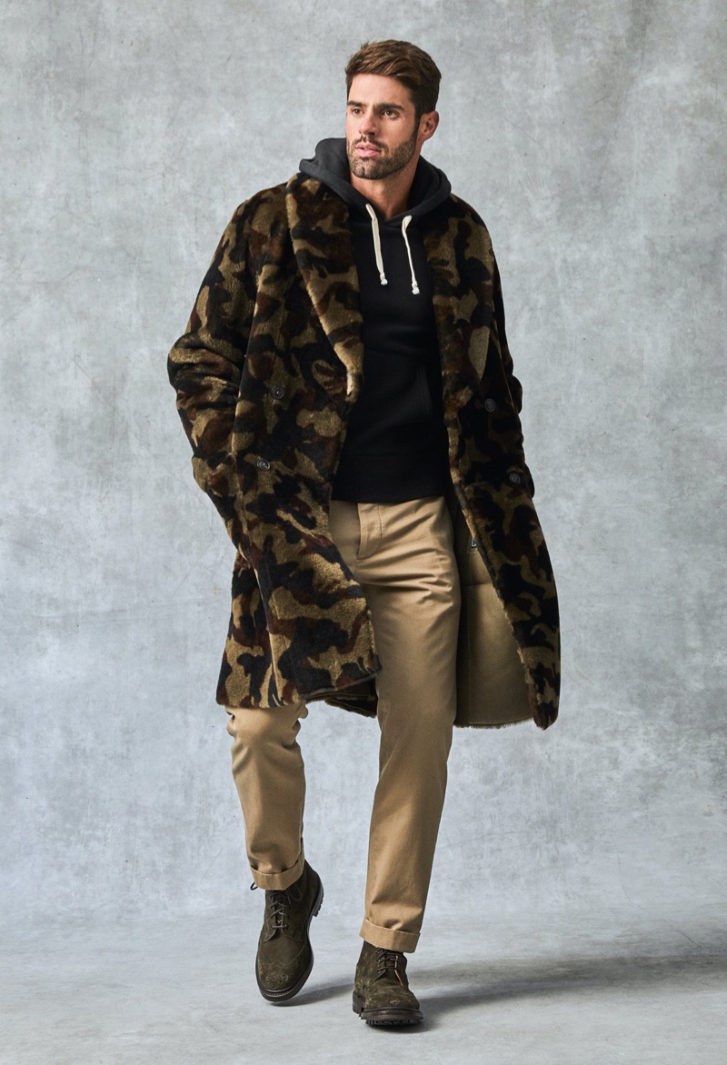 Making a graphic statement, Chad White models a Todd Snyder Italian shearling double-breasted shawl coat with a camouflage print. He also dons a Todd Snyder + Champion full-zip hoodie, Todd Snyder slim-fit tab front stretch chinos, and Tricker's + Todd Snyder stow boots.