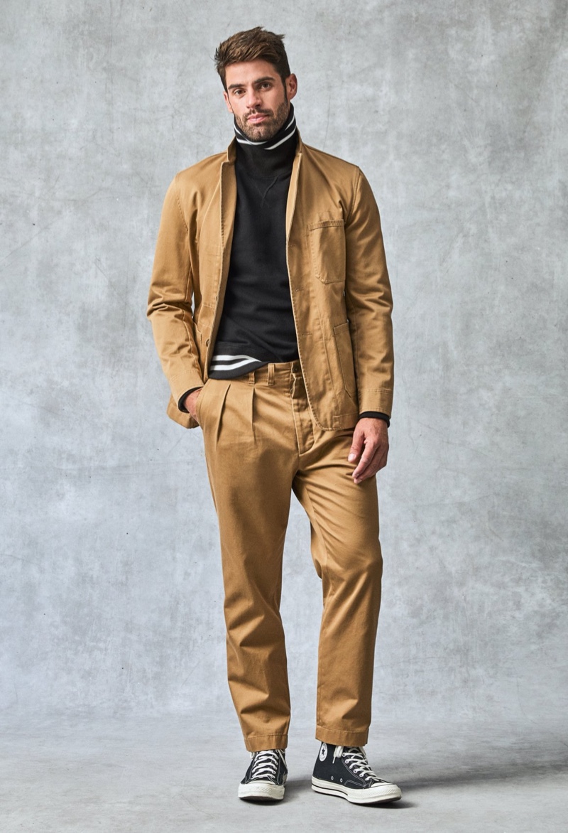 It's time for khaki as Chad White sports a Todd Snyder Japanese workwear suit jacket and chinos. A Todd Snyder + Champion tipped turtleneck sweatshirt and Converse Chuck 70 high-top sneakers complete his look.