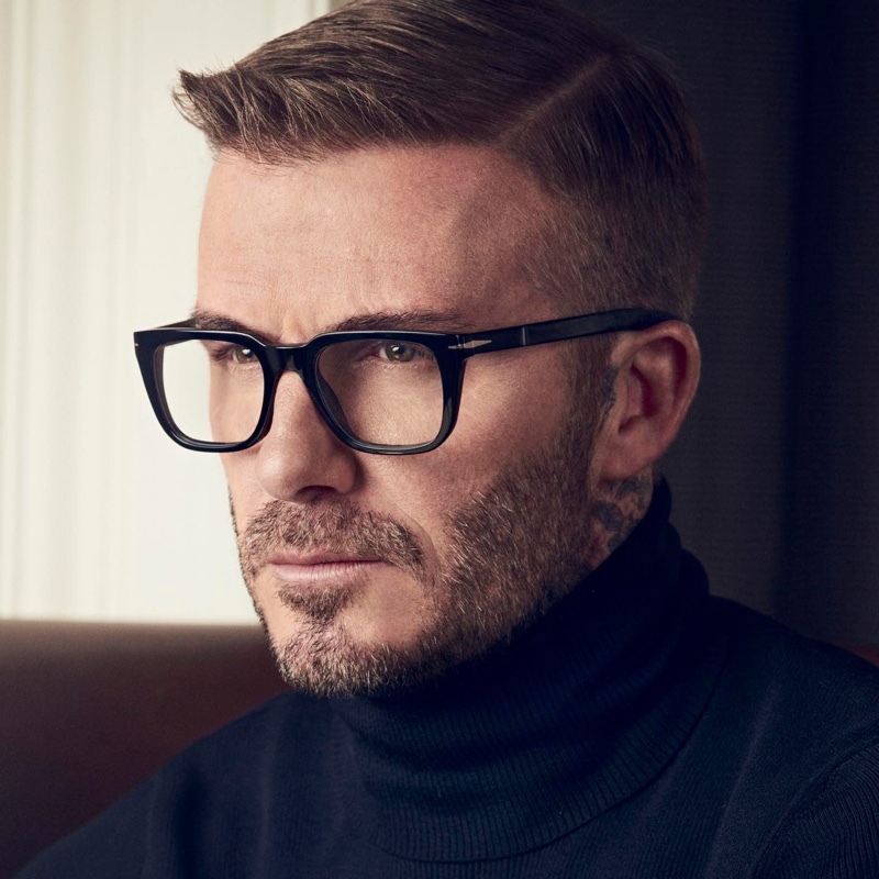 Ready for his close-up, David Beckham dons a navy turtleneck sweater with transparent gray DB 7070 glasses.
