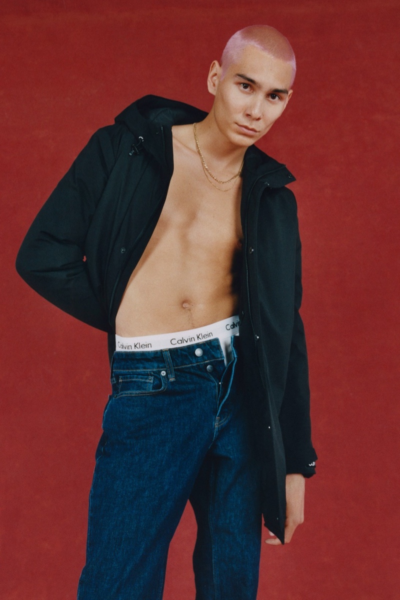 In front and center, Evan Mock sports a black jacket and blue jeans for Calvin Klein's holiday 2021 campaign.