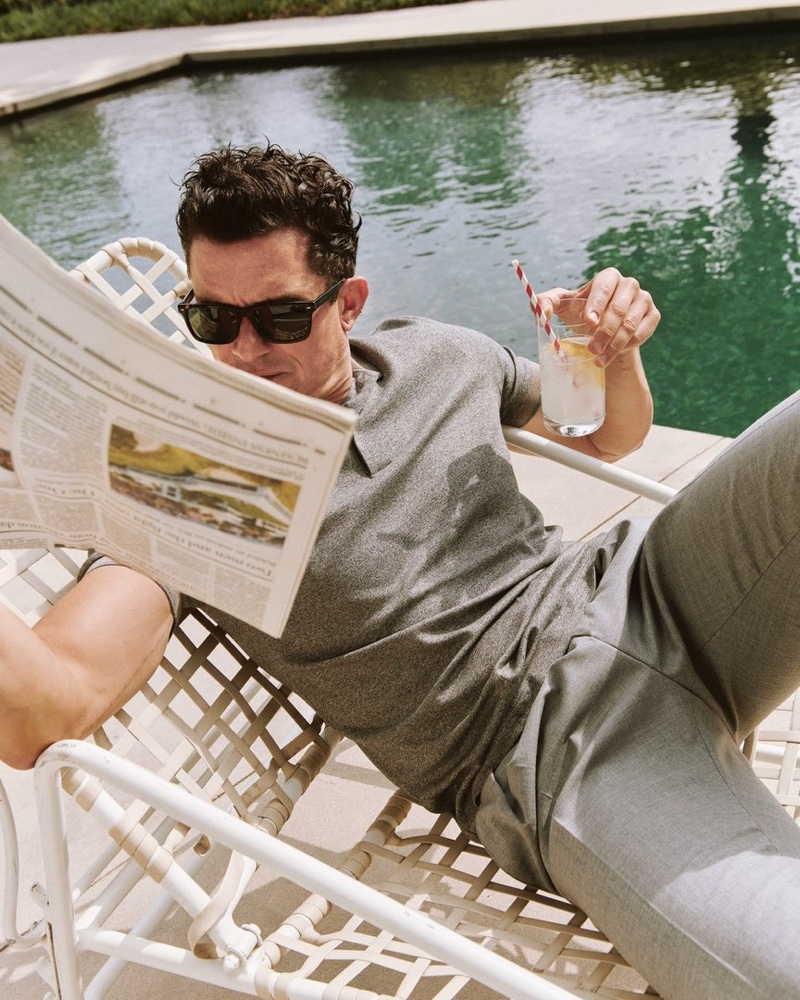 Relaxing poolside, Orlando Bloom wears a gray Hugo Boss look with BOSS sunglasses for Esquire.