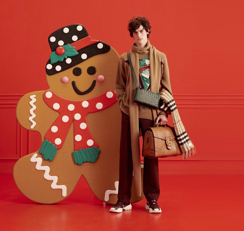 Geoffroy Noraz poses with an oversized gingerbread man for YOOX's holiday 2021 gift guide.