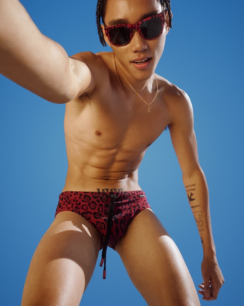 Marcelo Zhang embraces his wild side in a red and black animal print Dolce & Gabbana swimsuit for the brand's 2022 beachwear campaign.