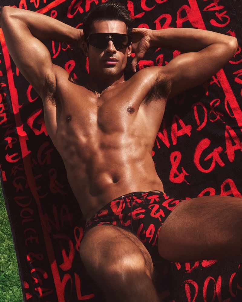 Elliot Meeten dons a red and black Dolce & Gabbana print swimsuit for the Italian brand's 2022 beachwear campaign.