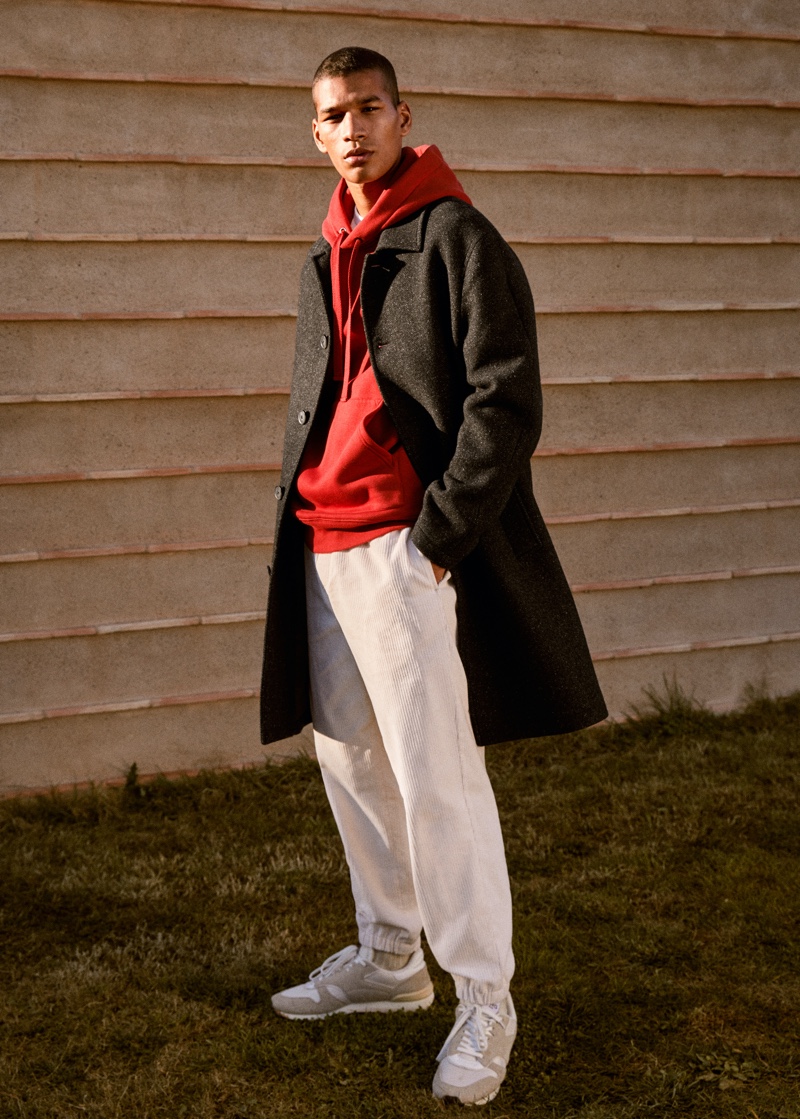 Hamady Hirailles wears a single-breasted coat over a hoodie and corduroy pants from Mango.
