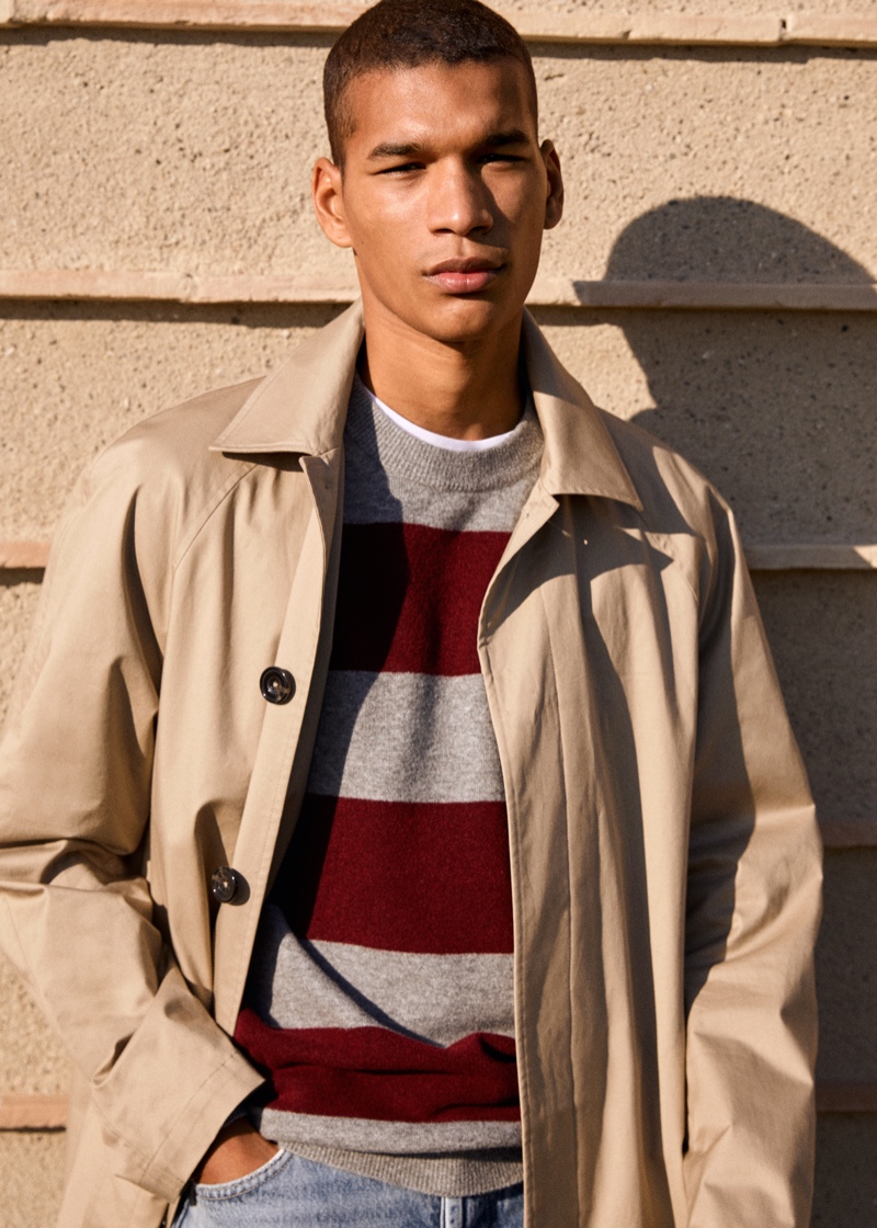 Donning a classic trench, Hamady Hirailles also wears a striped crewneck sweater and jeans from Mango.