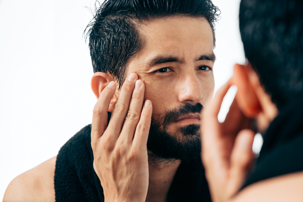 Mature Man Looking in Mirror at Face