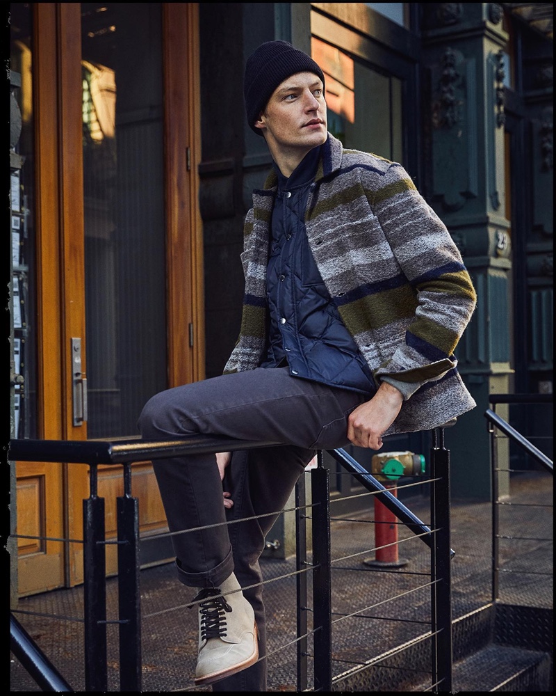 Model Roberto Sipos steps out in a Todd Snyder blanket stripe knit chore coat, an Italian recycled cashmere beanie, a Japanese down quilted vest, Japanese selvedge chinos, and Alden suede Indy boots.