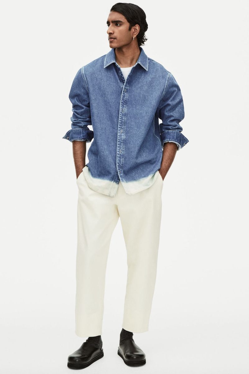 Jeenu Mahadevan dons an ombré denim shirt with white jeans for COS' spring 2022 denim campaign.