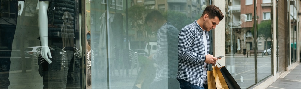 Man Outside Store with Bags on Phone