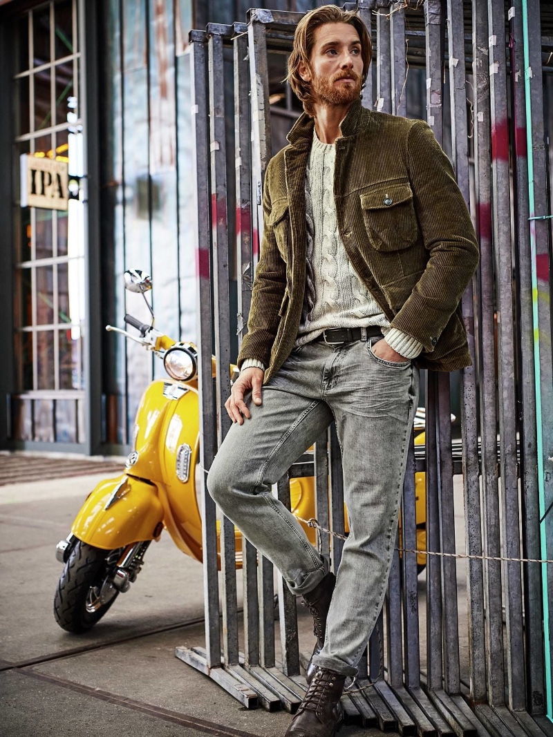 Tom Busson poses in a corduroy jacket with a cable-knit sweater and jeans from Mey & Edlich.