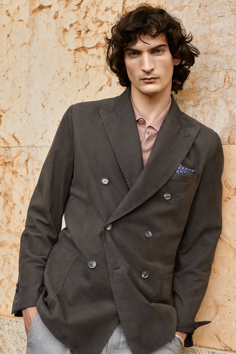 Luca Lemaire dons a double-breasted jacket over a polo and light gray trousers by Brioni.