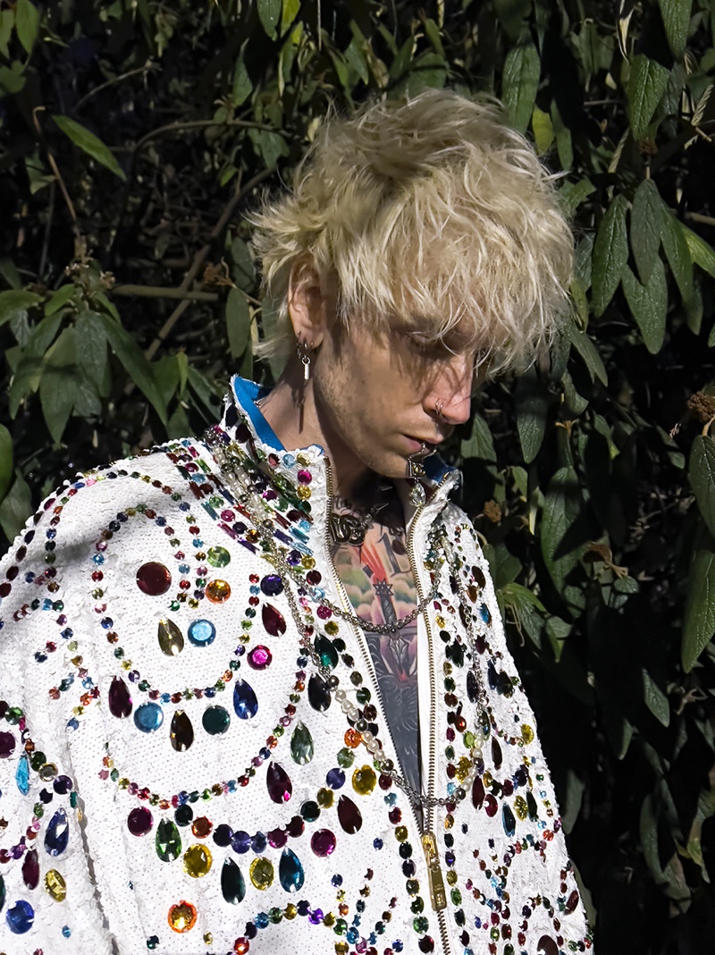 Music artist Machine Gun Kelly connects with Dolce & Gabbana for spring-summer 2022, wearing the brand's sequin jacket that is embellished with multi-colored stones. He accessorizes with Dolce & Gabbana jewelry.