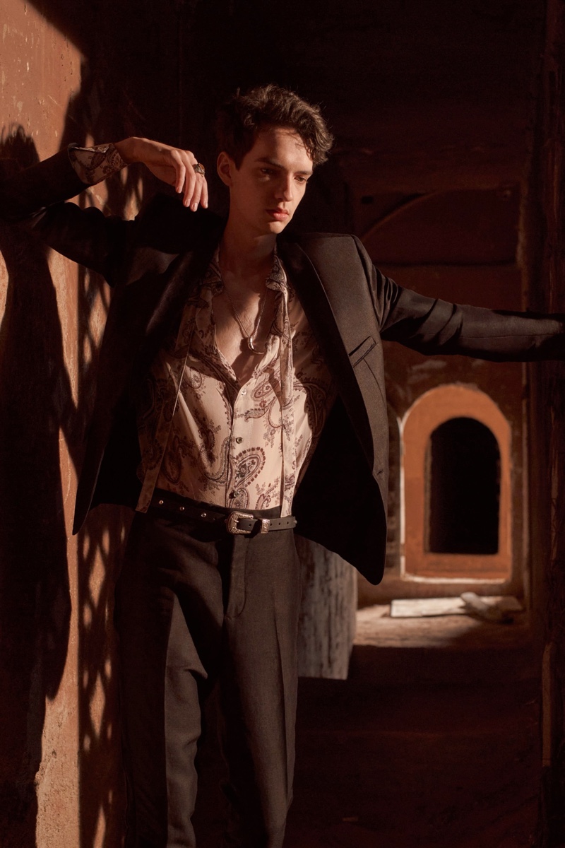 Actor Kodi Smit-McPhee wears a black tuxedo suit with a paisley printed shirt and rhinestone black leather belt for Zara Man's spring-summer 2022 Studio collection campaign.