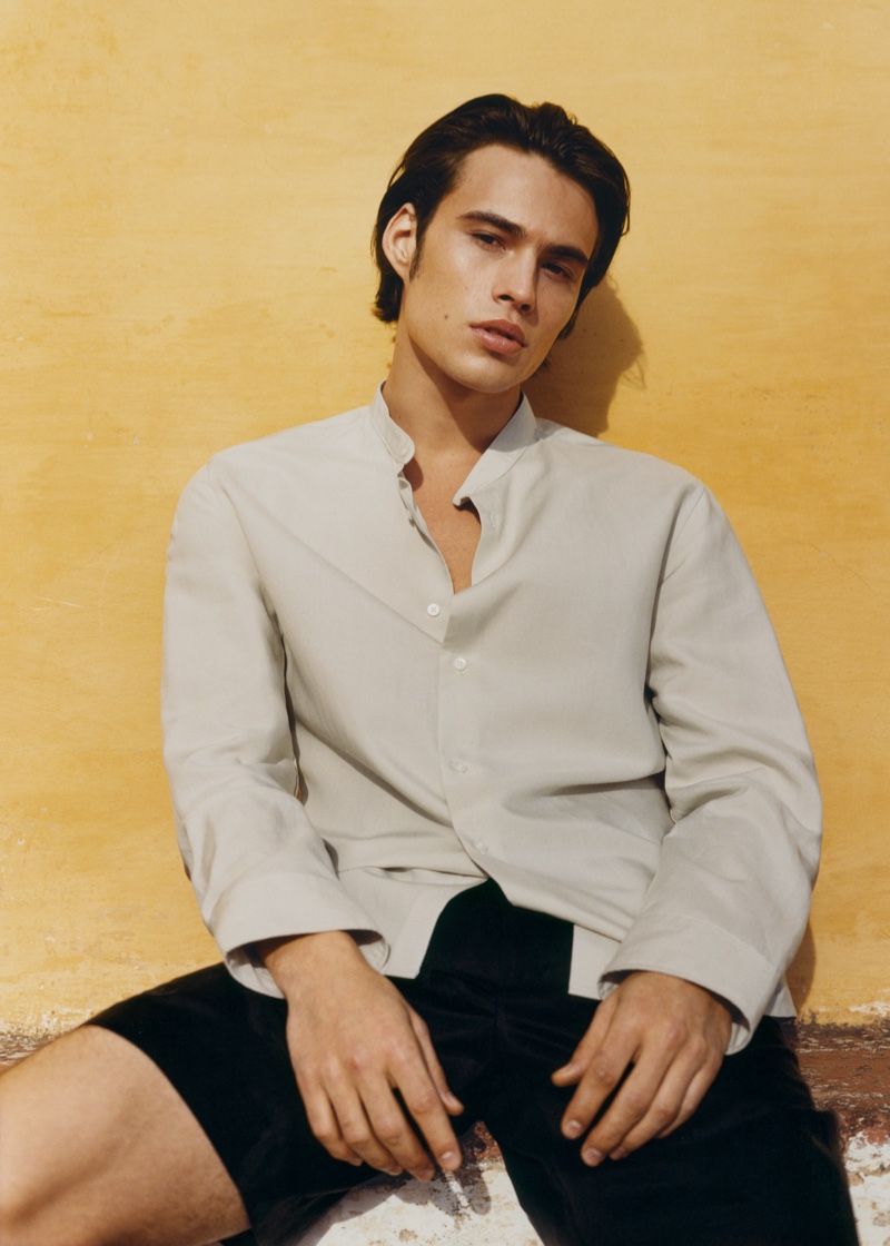 Embracing smart-casual style, Louis Baines models a band-collar long-sleeve shirt with shorts from Mango Man.