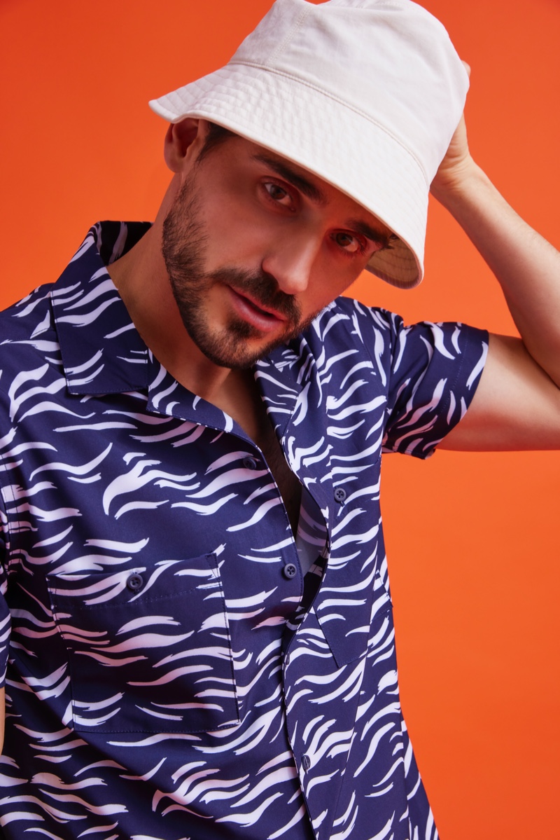 Model Arthur Kulkov embraces a summer vibe in a printed shirt and bucket hat from Onia.